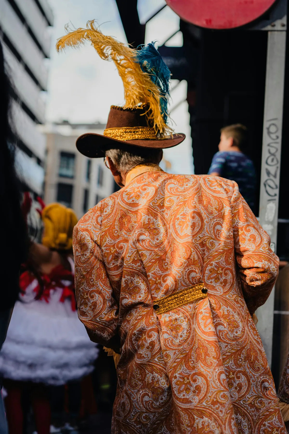 A carnival-goer in a patterned coat and feathered hat during the Las Palmas Carnival