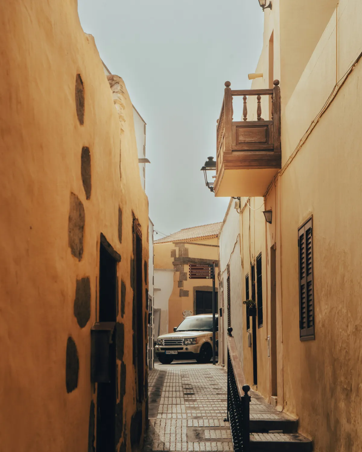 A narrow street in the old town of Agüimes, with ochre façades and a wooden balcony