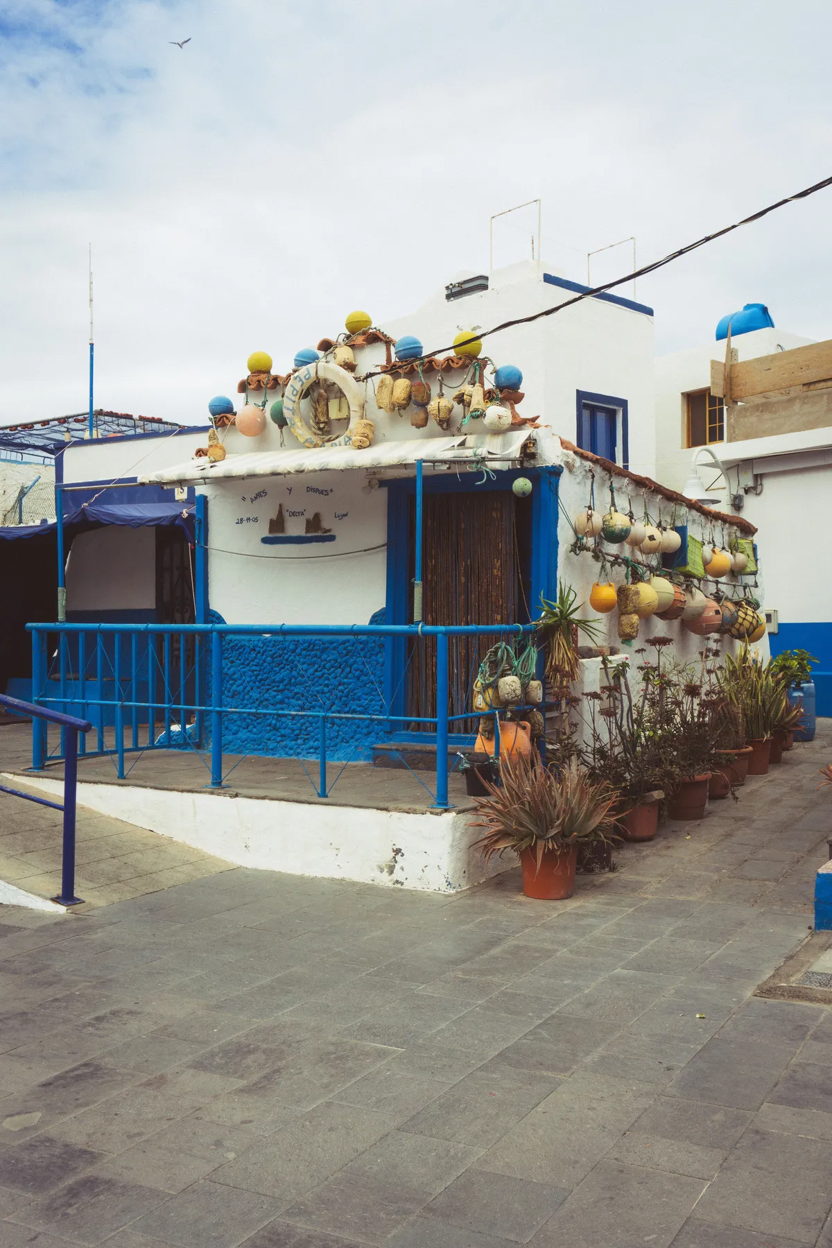 A white and blue fishermen’s house decorated with colourful buoys and plant pots in Puerto de las Nieves