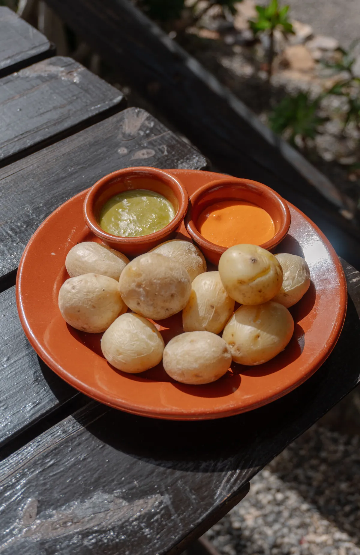 Plato de papas arrugadas con dos cuencos de mojo, verde y rojo