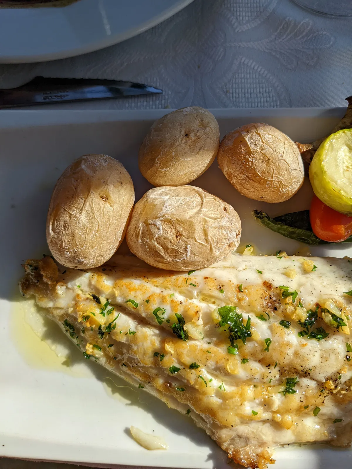 Filete de pescado a la plancha con perejil, servido con papas arrugadas y verduras