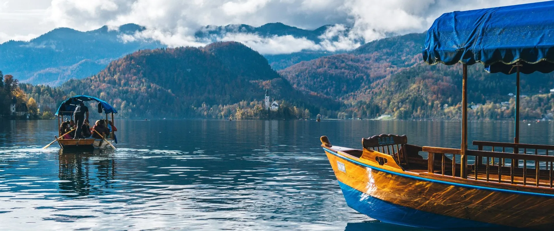 Barcas tradicionales de madera en el lago de Bled (Eslovenia), con la iglesia del islote al fondo